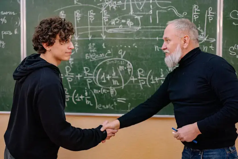 Un profesor estrechando la mano de su alumno.
