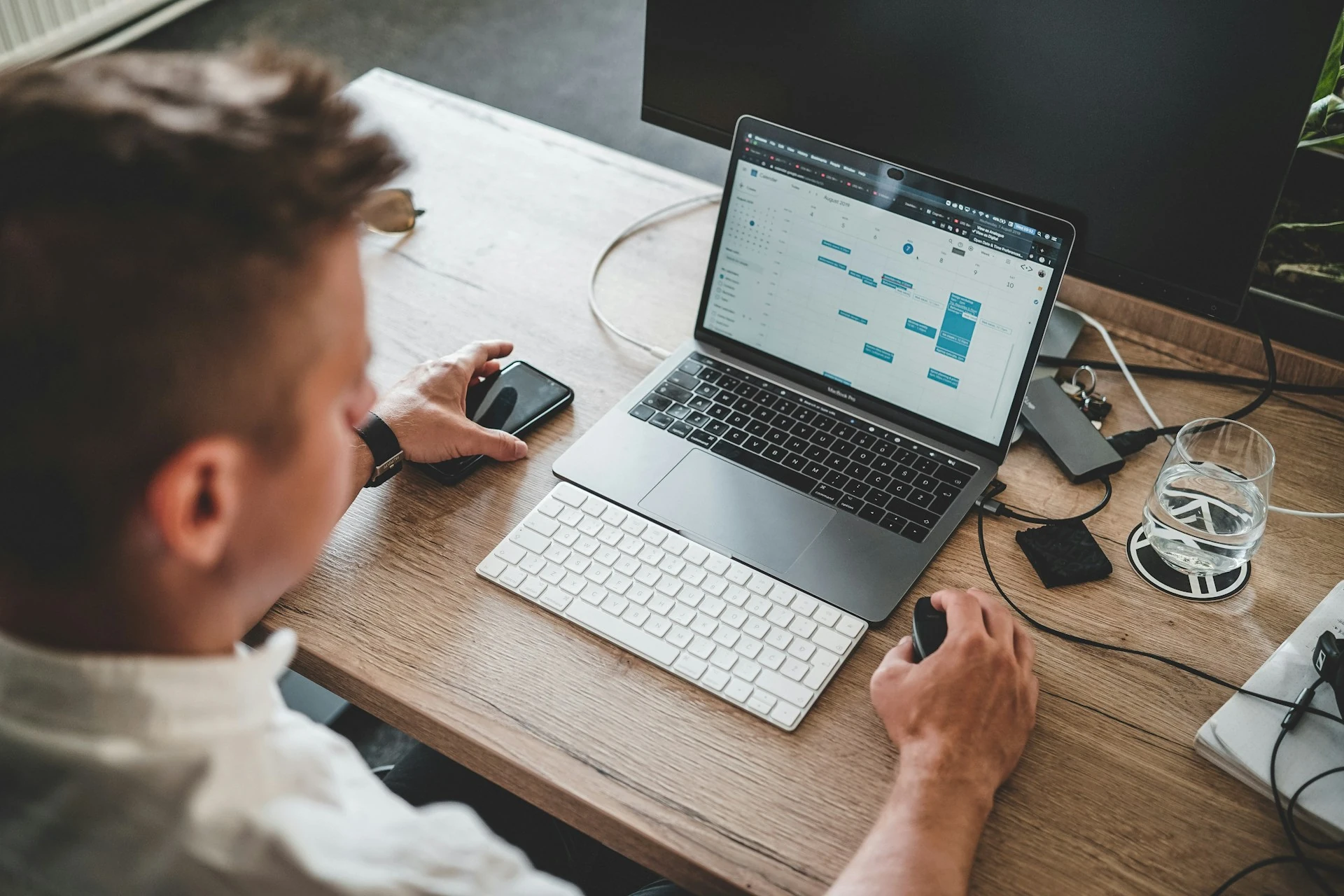A man working on a calendar schedule on his laptop.