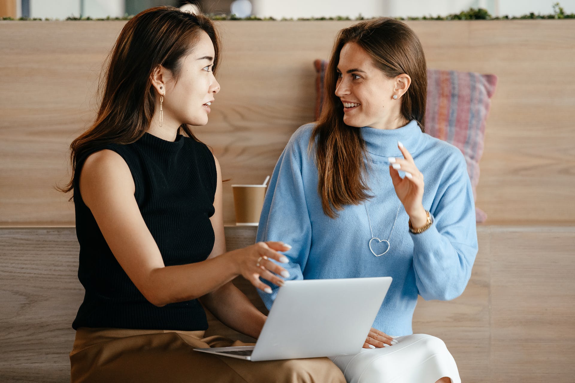 Two women discussing something on their laptop. Photo by Alexander Suhorucov.