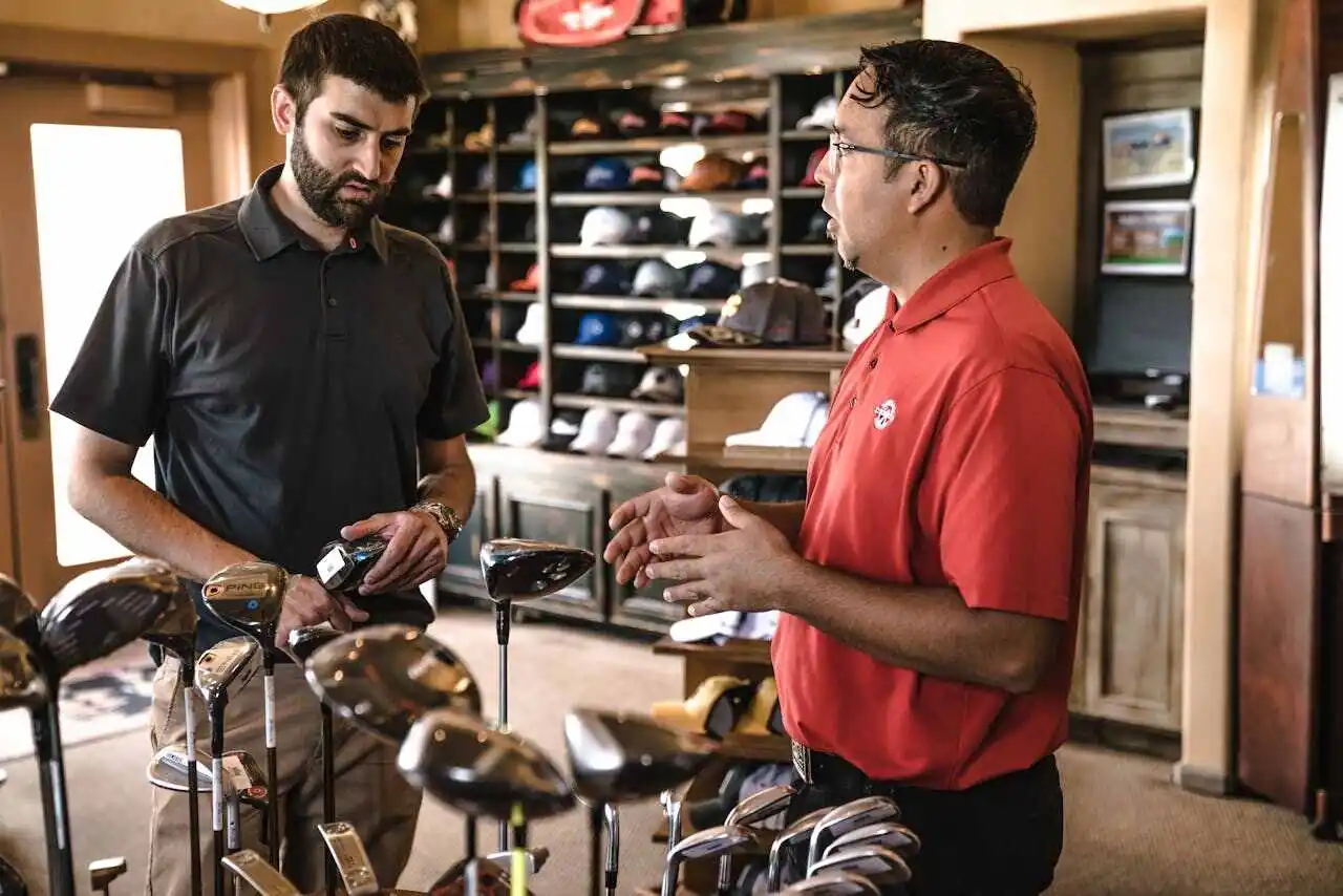 Two men talking in a golf store.