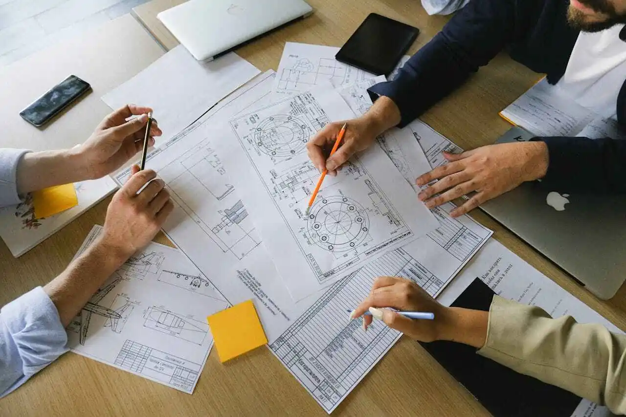 Businesspeople with pens in hands examining documents.