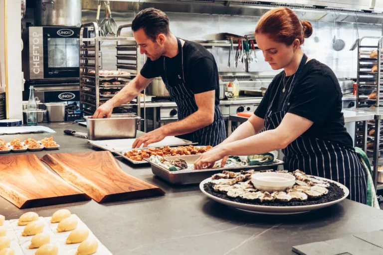 Restaurant workers assembling food on trays. Time Tracking Best Practices in US Restaurants