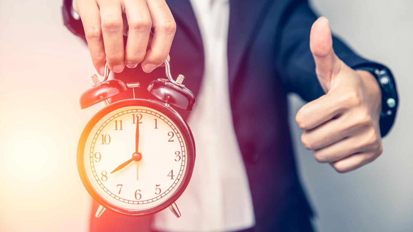 A man in a suit holding up a clock.