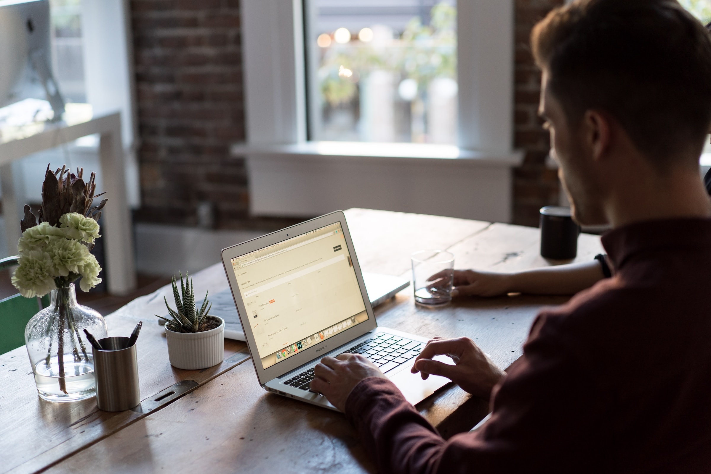 A man working on his laptop placed on a wooden table. Photo by Bench Accounting on Unsplash