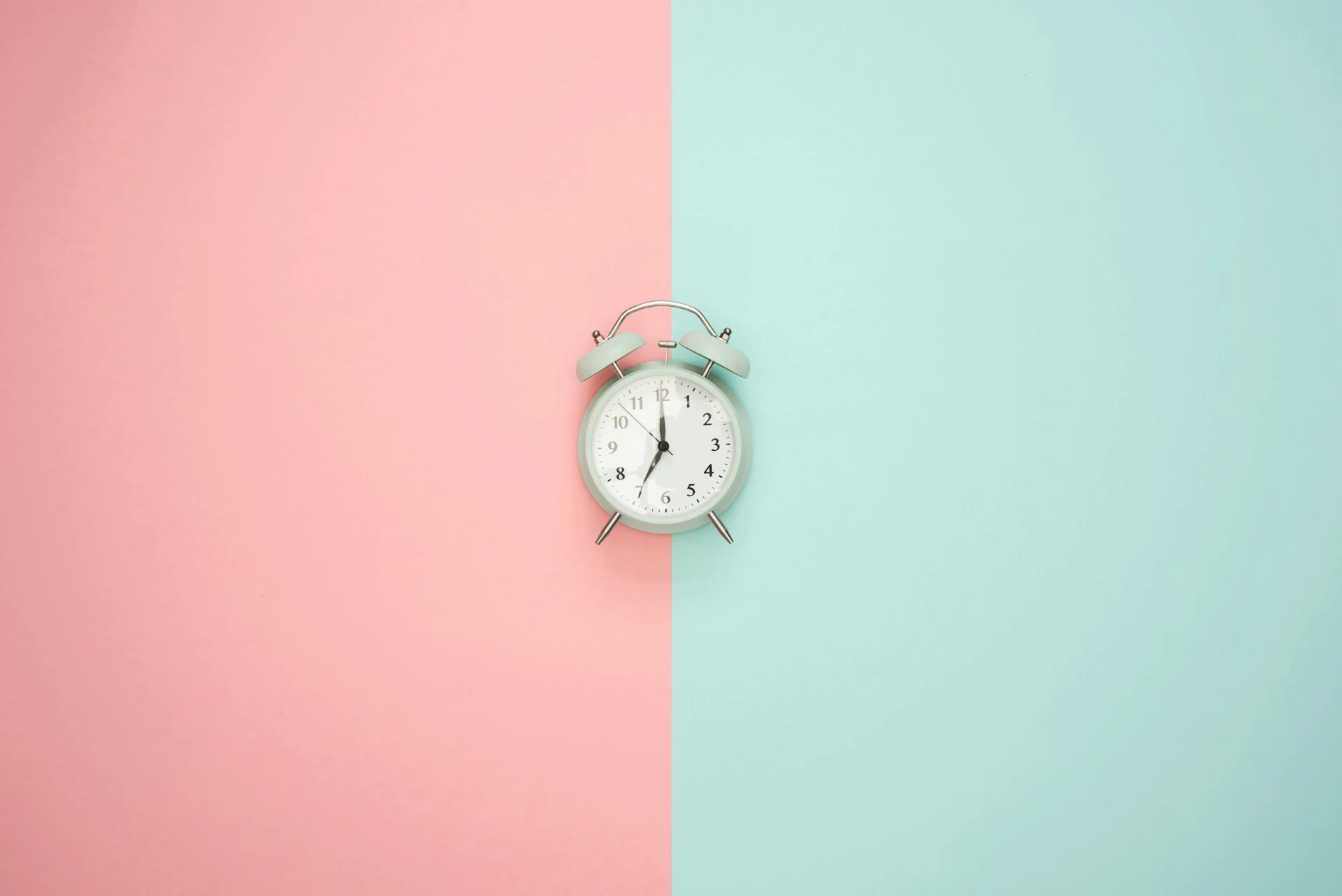A clock placed on a pink and blue background.