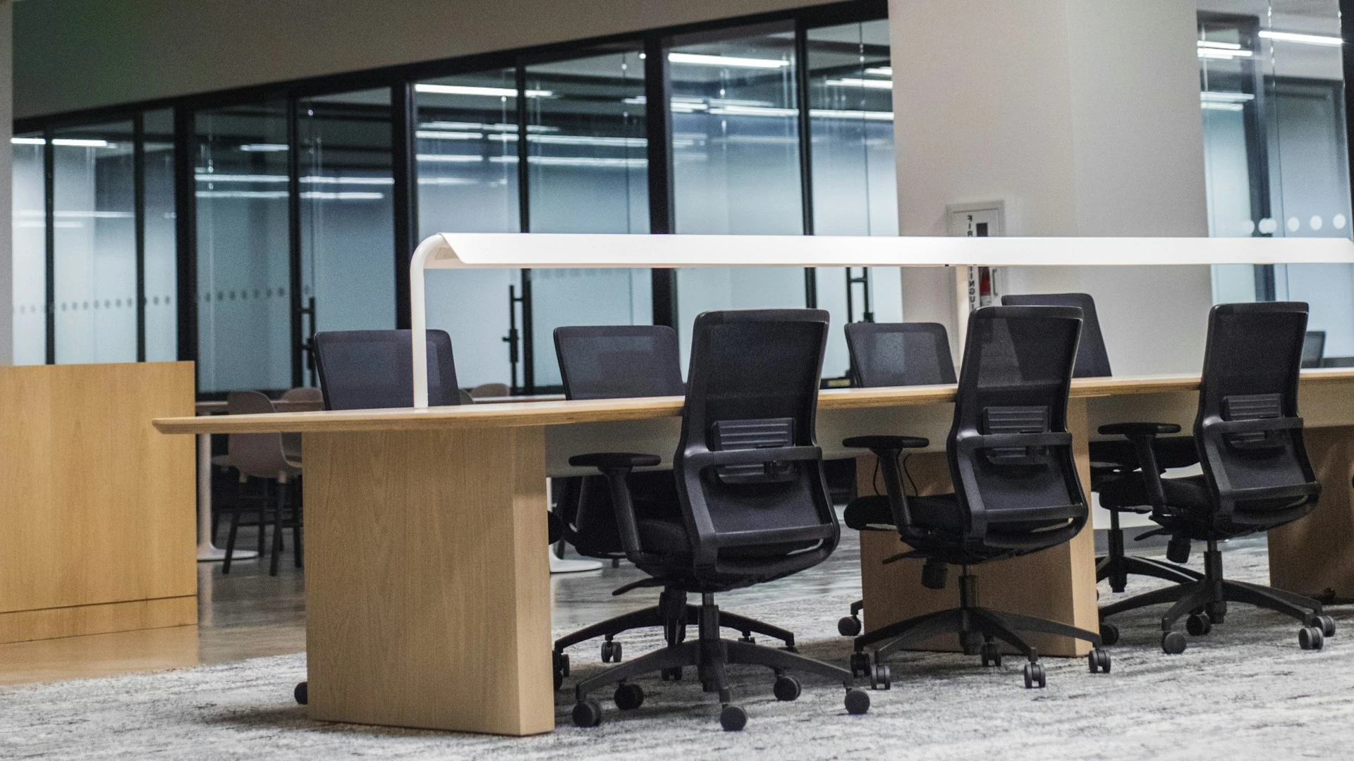 An empty office with desks and black office chairs.