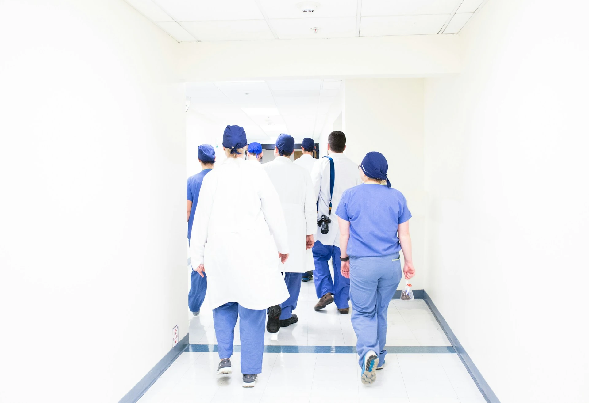 Doctors and nurses in uniform walking across a hallway.