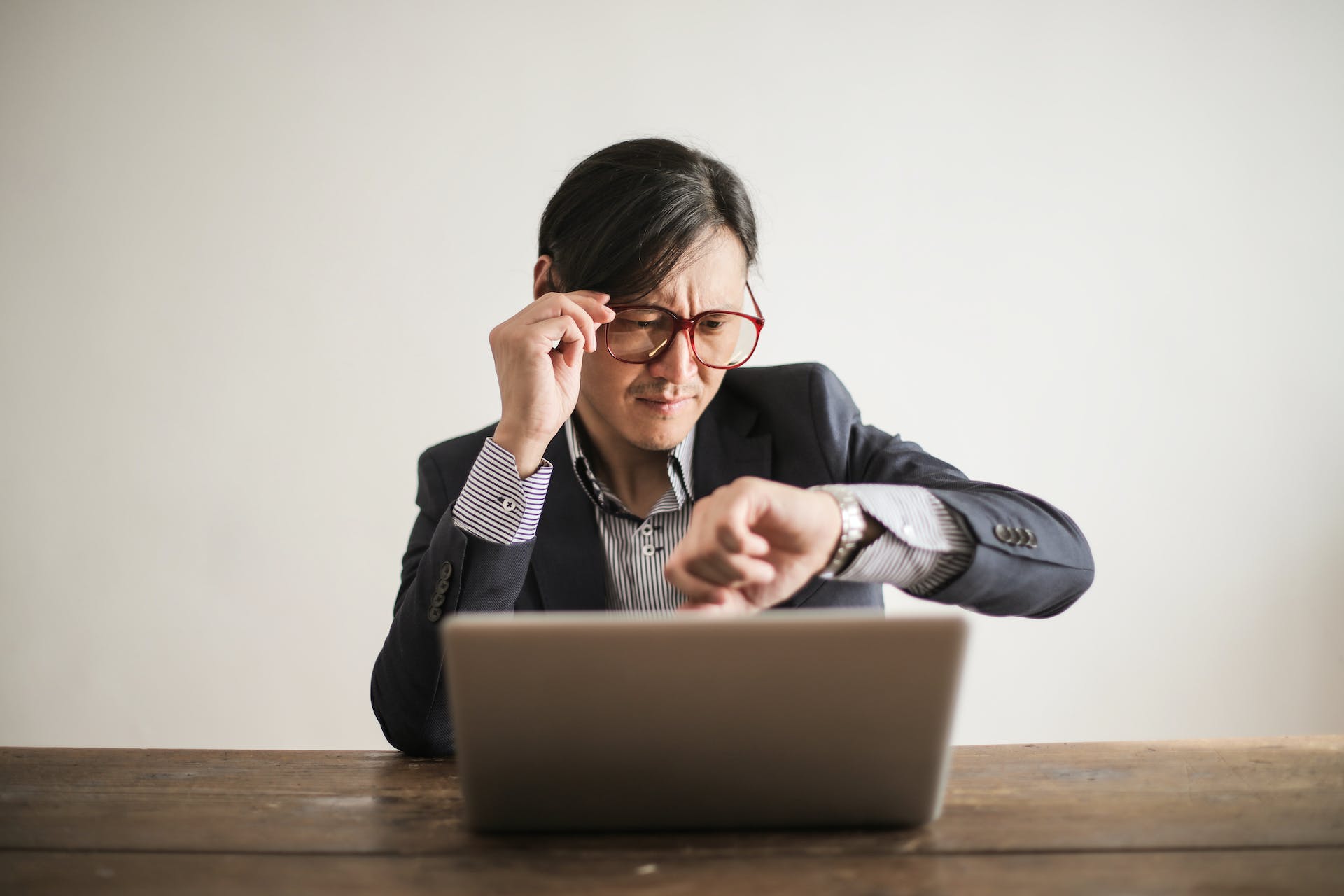 A guy wearing glasses checking his wrist watch.