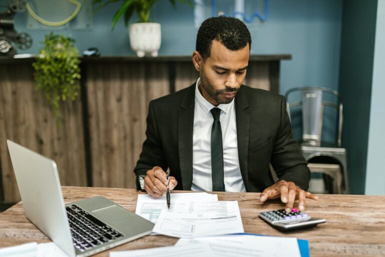 Calculating Time for Work. Photo by RDNE Stock project: https://www.pexels.com/photo/man-in-black-suit-working-7821702/