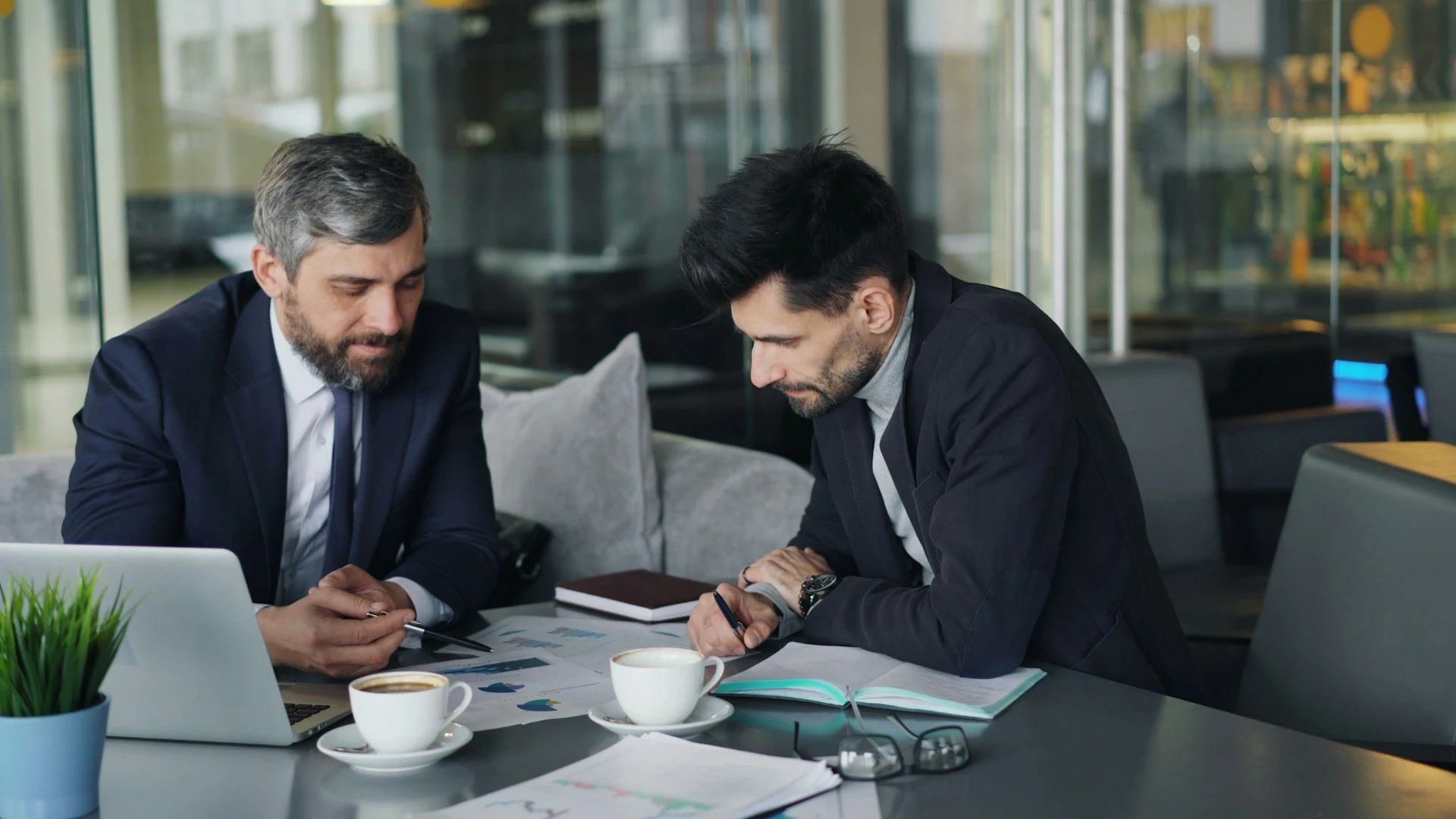 Two male employees in suits discussing something at work