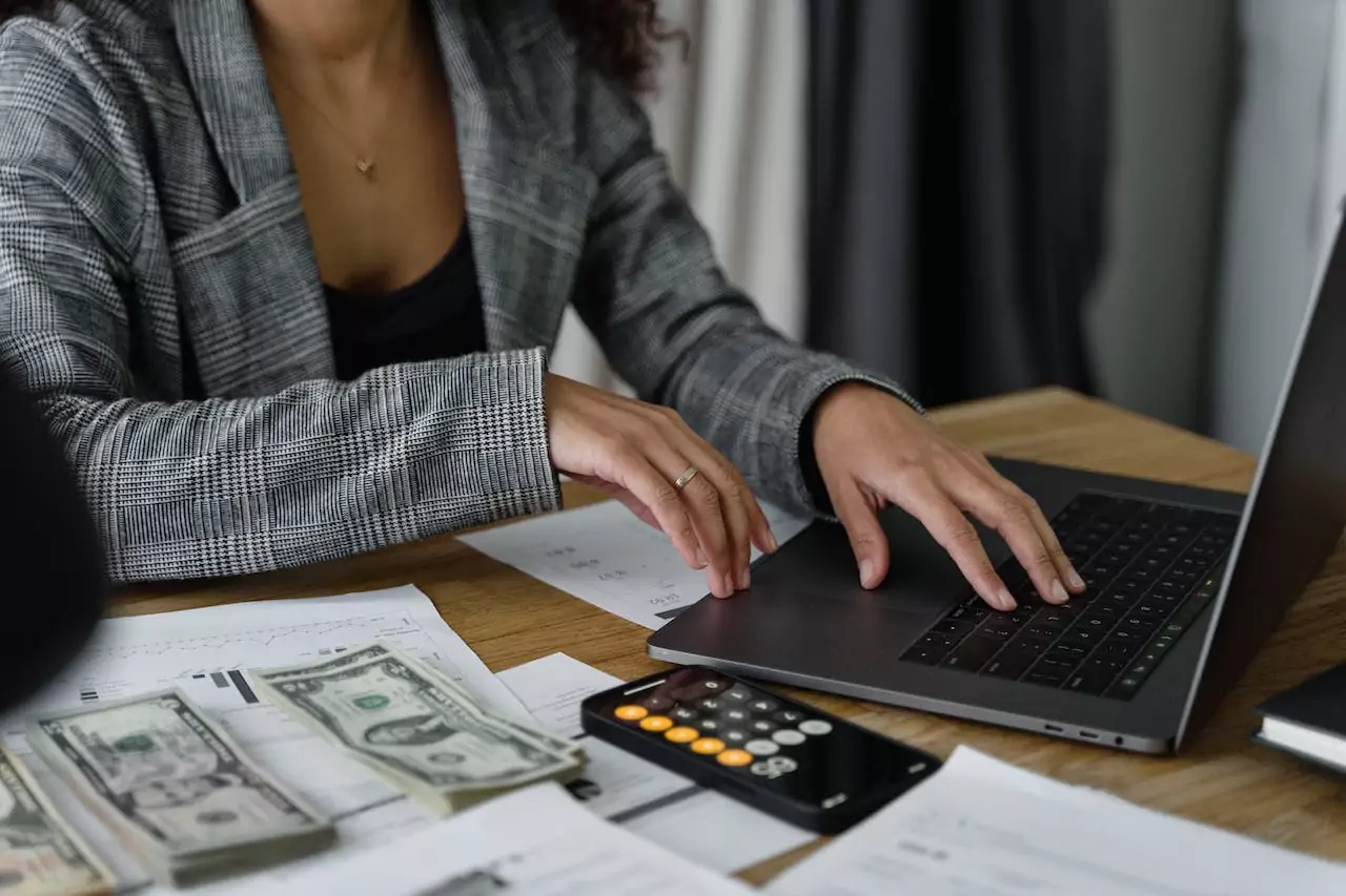 A woman analyzing company revenue and working on her laptop.