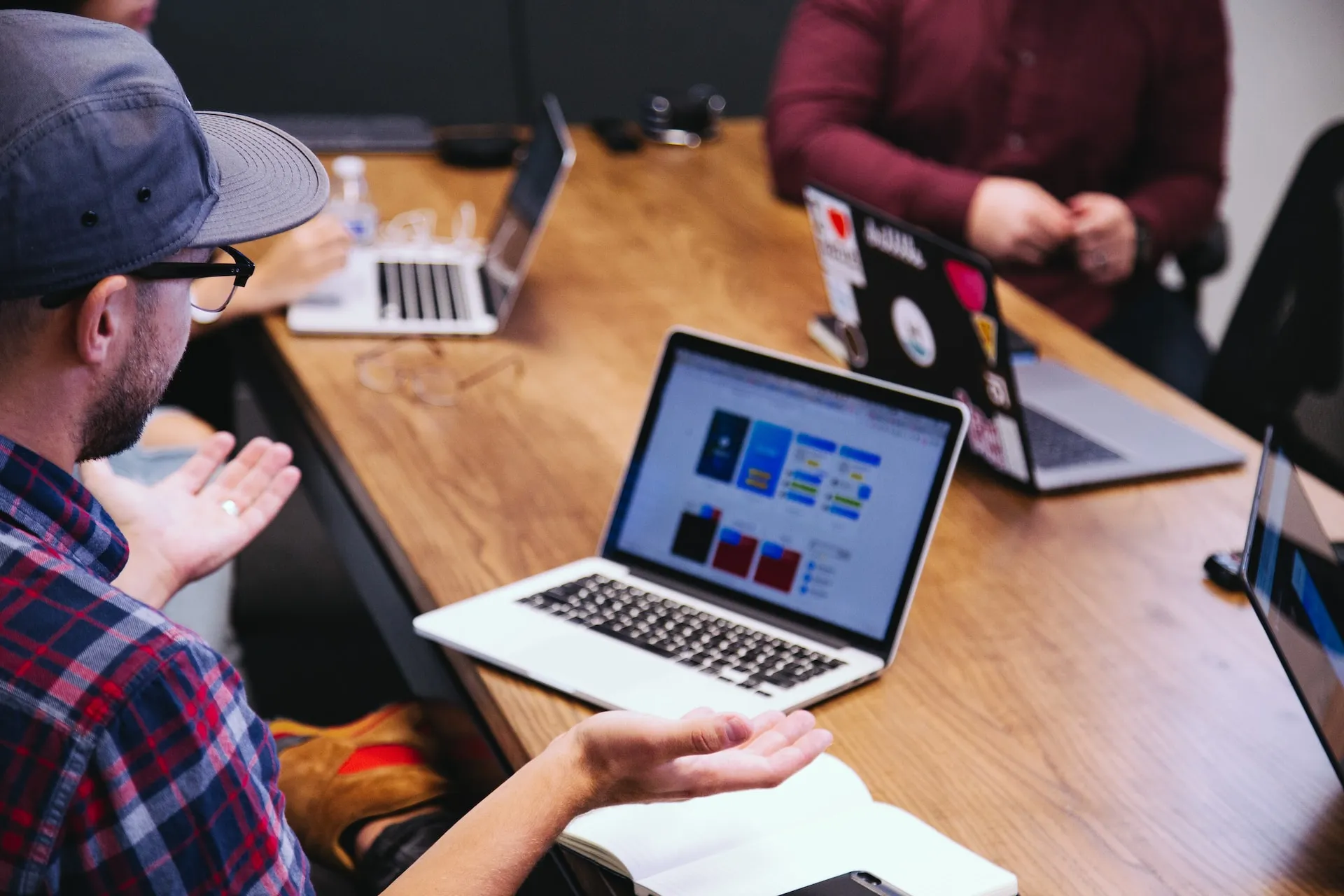 A man discussing something to the team while sitting in front of his laptop.