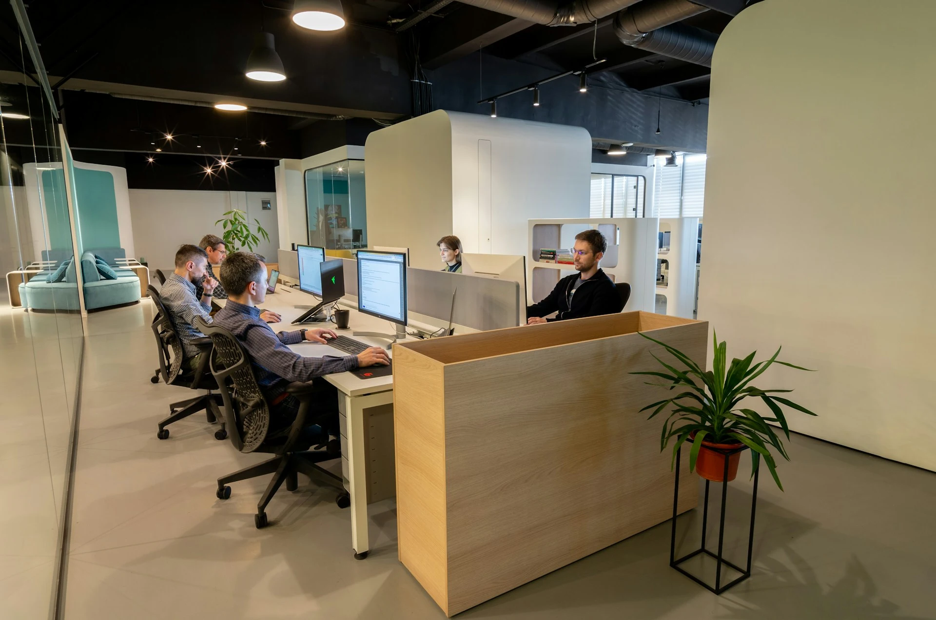 A group of people sit at desks in an office.