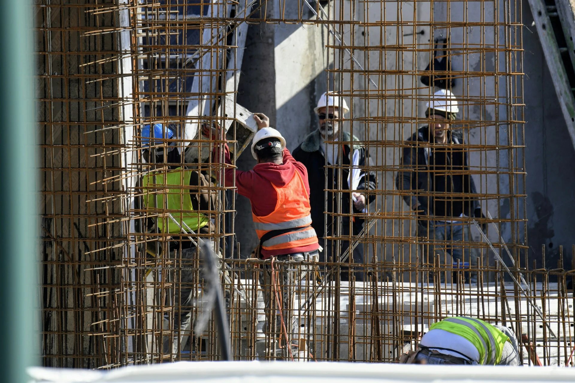 A group of constrution workers stand behind steel works.