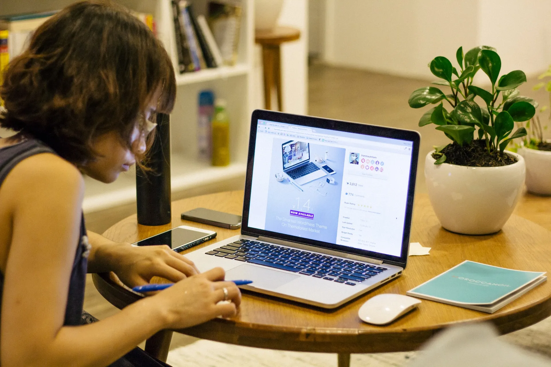 Una mujer trabajando en su computadora portátil mientras toma notas. Foto de Tran Mau Tri Tam ✪ en Unsplash