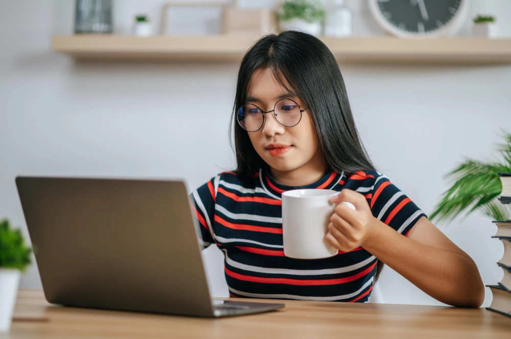 一位年轻女性在桌前使用笔记本电脑工作