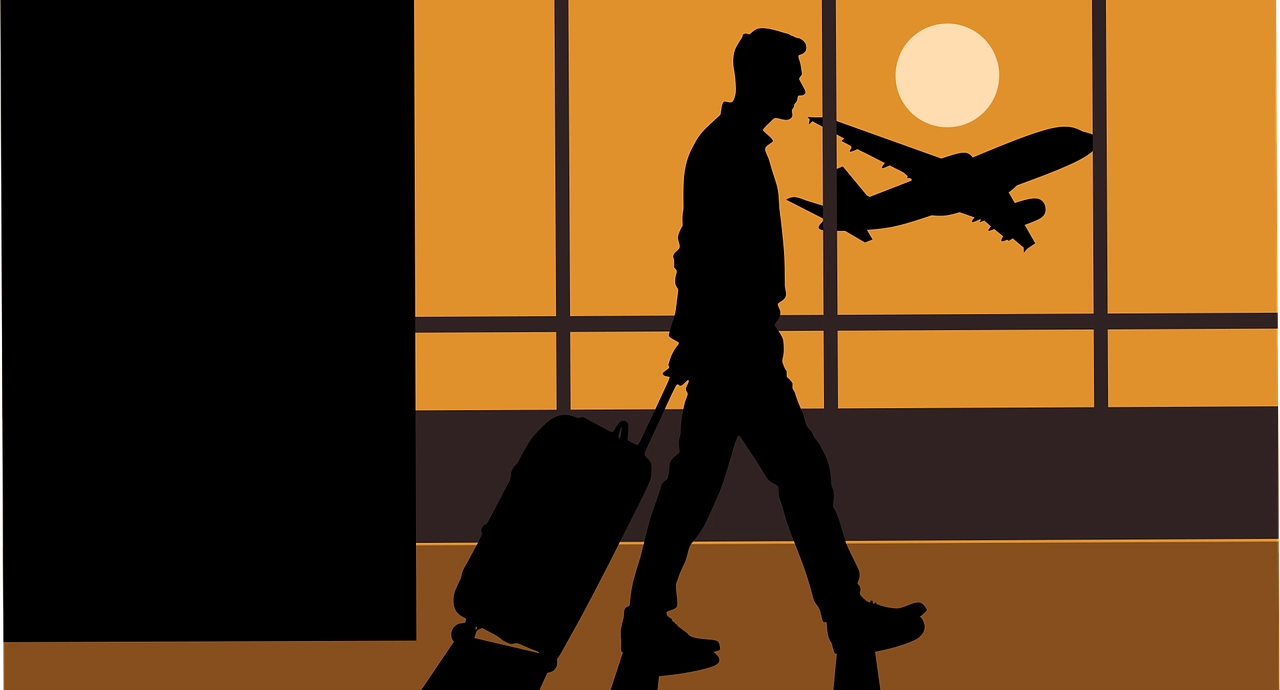 A man at the airport carrying his luggage.