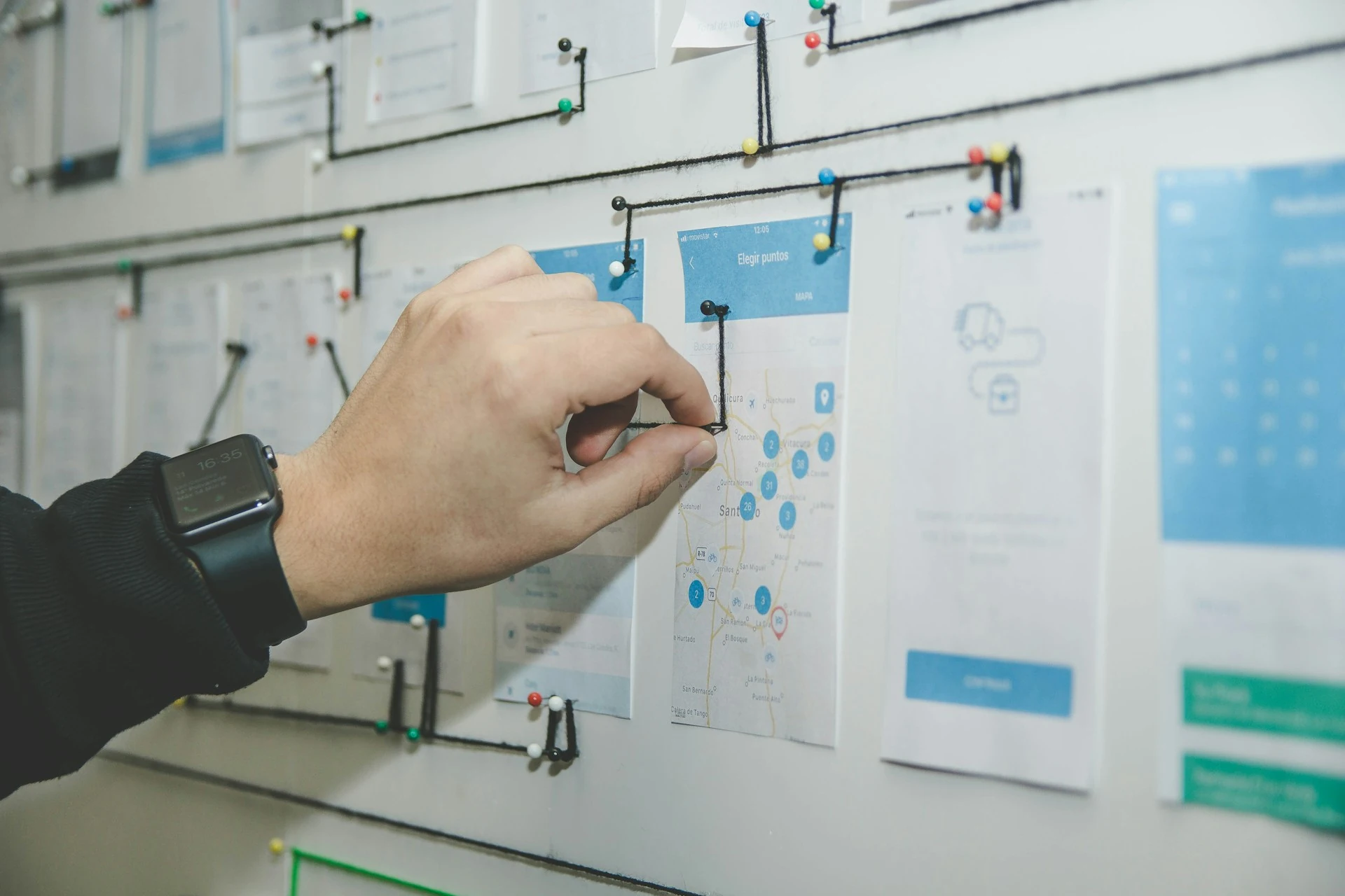 Someone pointing at notes pinned on a board.
