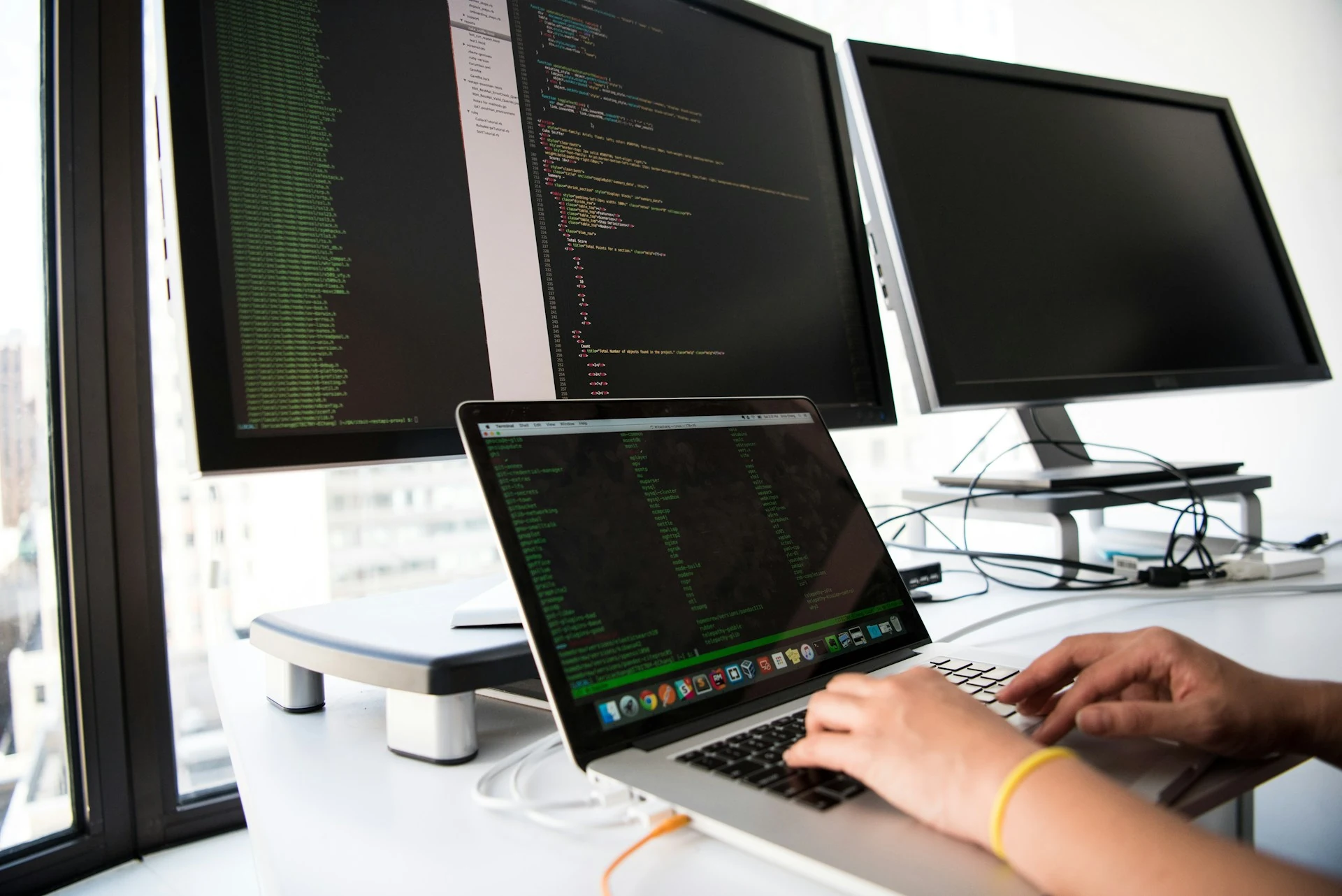 A person using a MacBook in a shallow-focus setting.