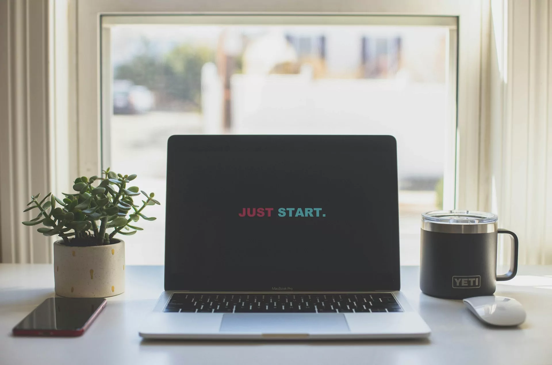 A laptop displaying the words "Just Start" on the screen.