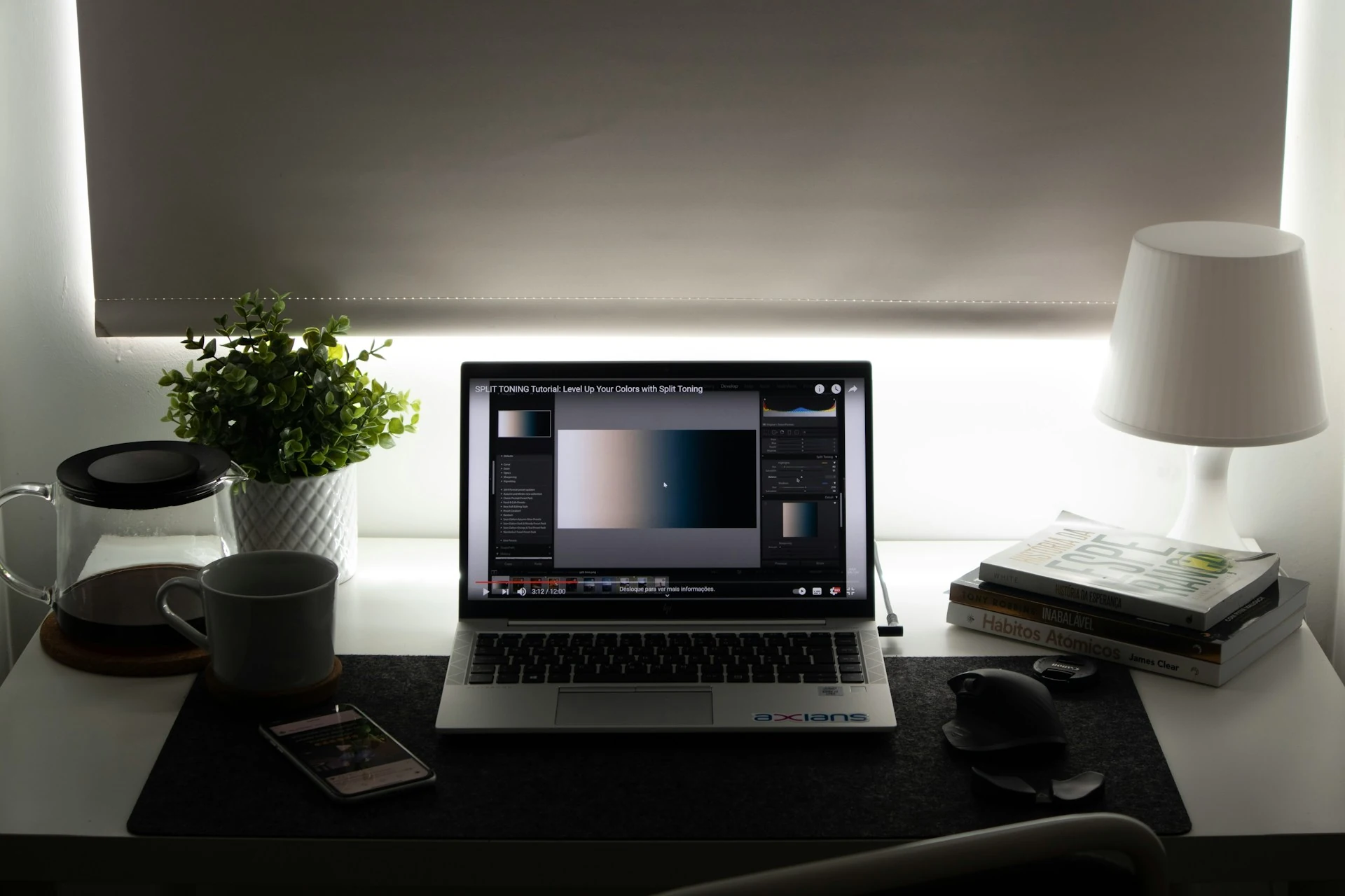 A work station with a laptop, a lamp, and books on the table.