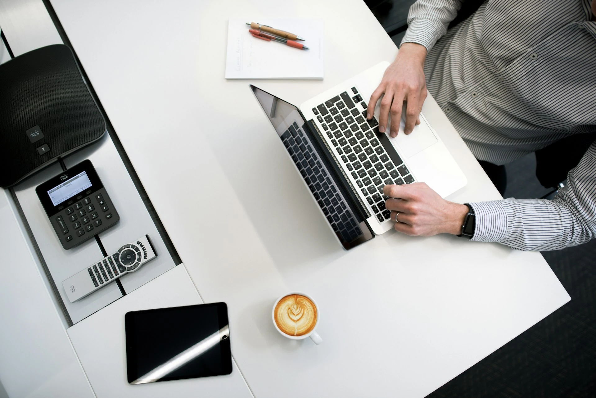 A man working on his laptop with a cup of coffee on his desk.