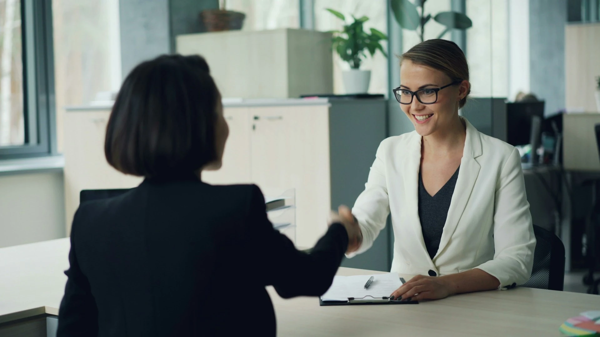 A woman shaking an applicant's hand.