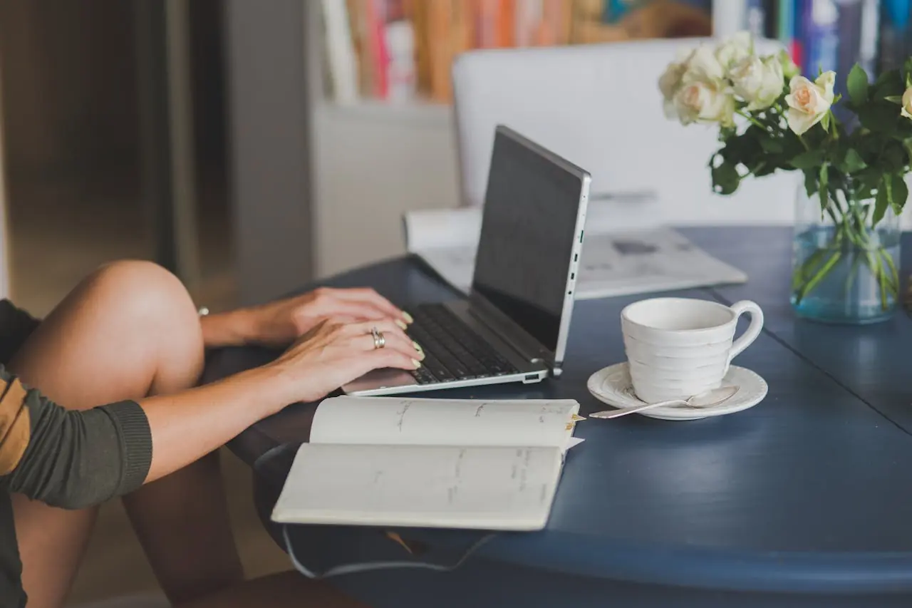 Someone working from home on their laptop with a cup of coffee placed next to the laptop.