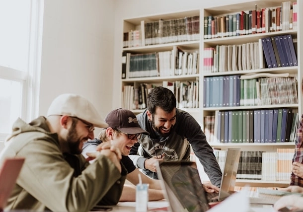 A group of employees laughing and working on their laptops at the office.