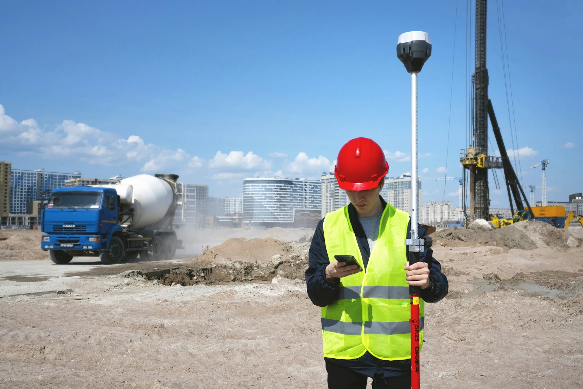 Construction worker with red hard hat looking at his mobile phone.