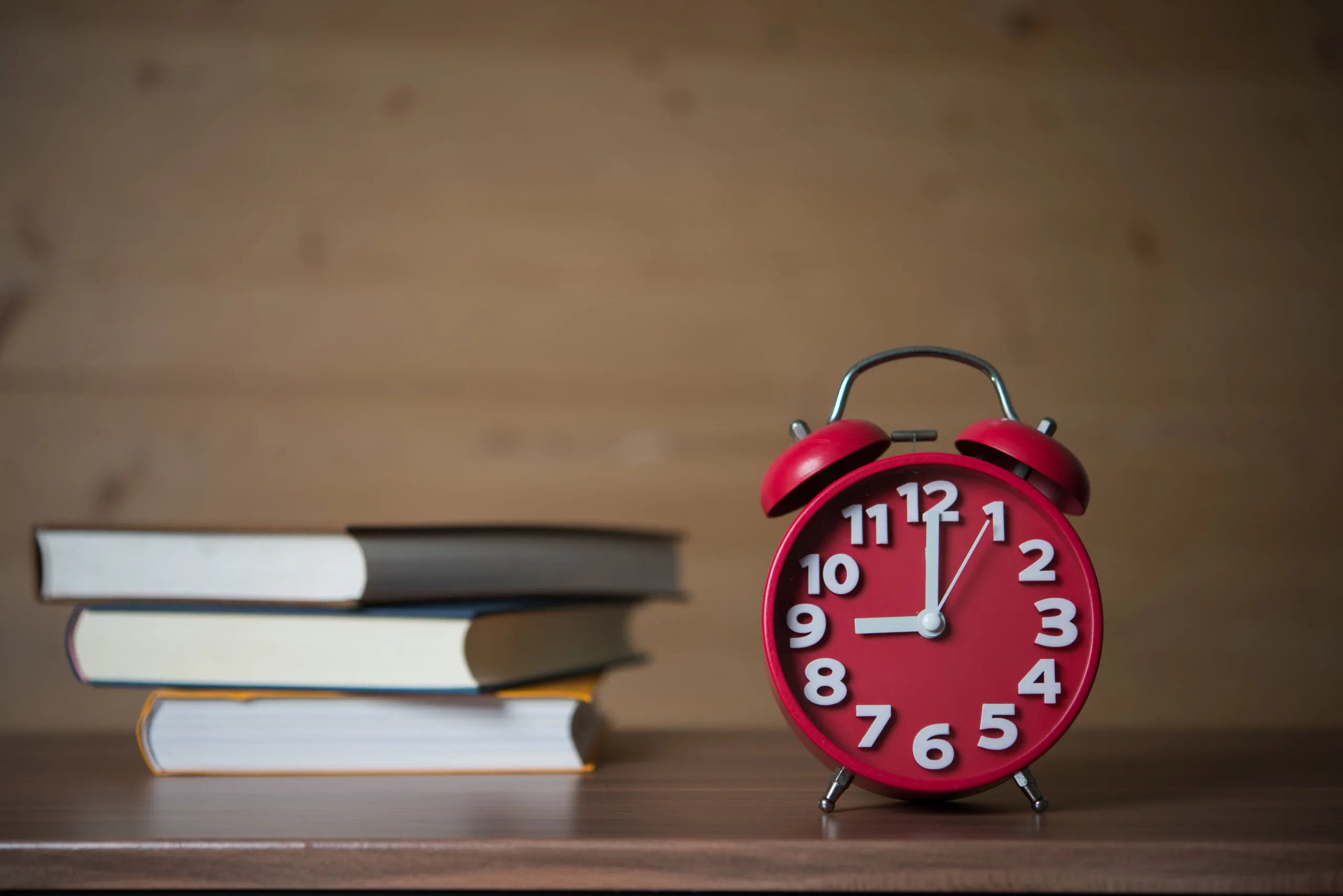 Sveglia che segna le 9 accanto a una pila di libri.