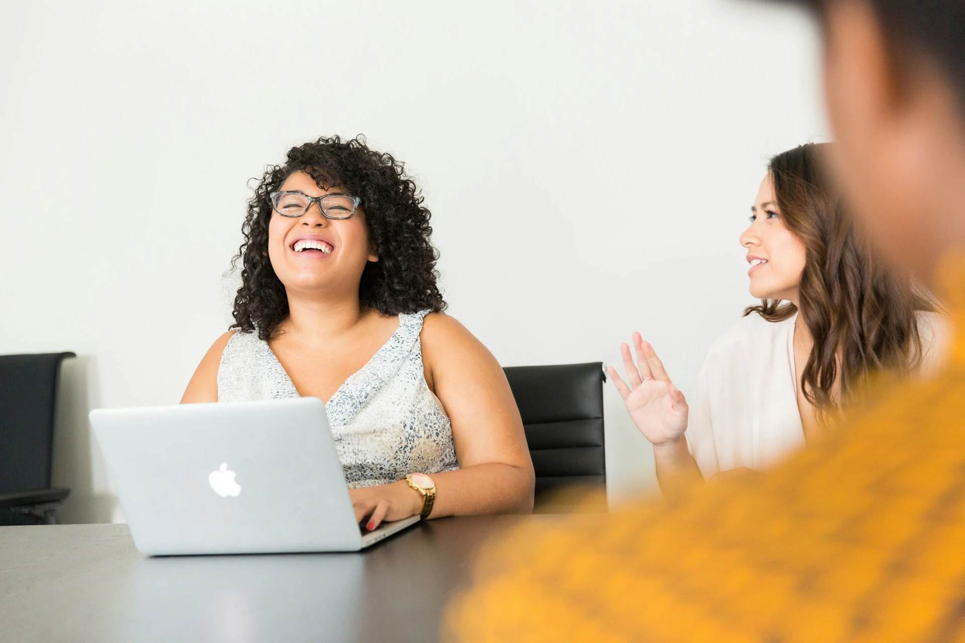 A woman laughing in front of her laptop.