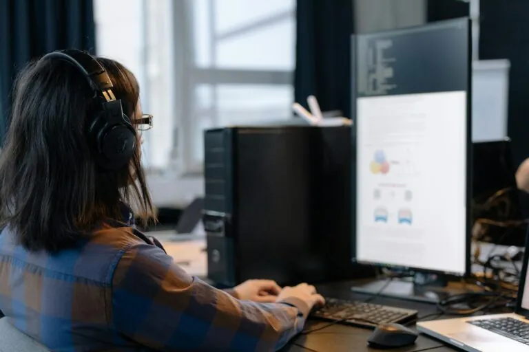 man working on his computer on a desk wearing headset