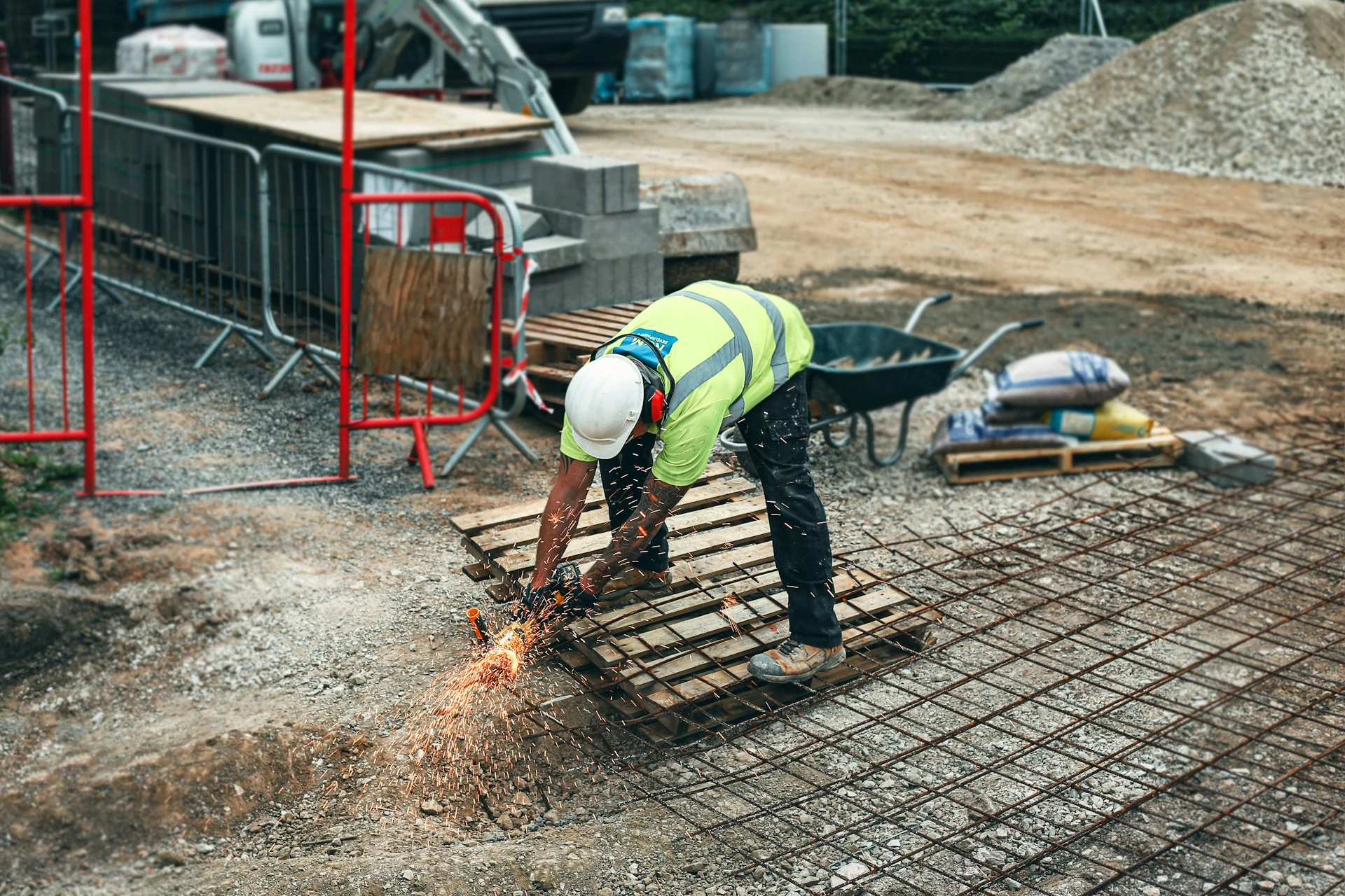 Construction workers working at a site, using a steel welding tool.
