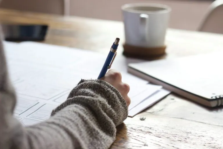 Person writing on paper at desk