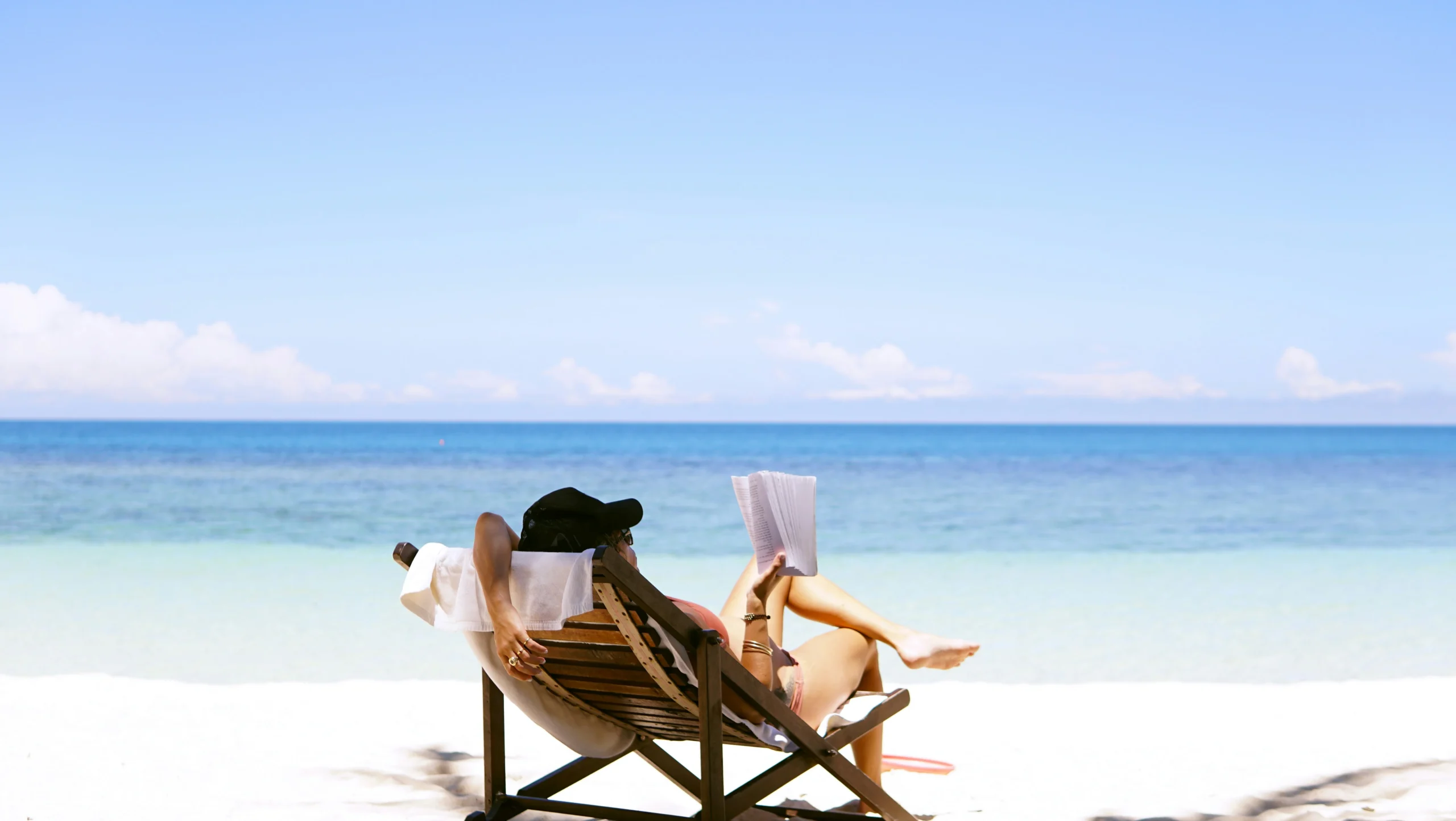 Donna che legge un libro in spiaggia.