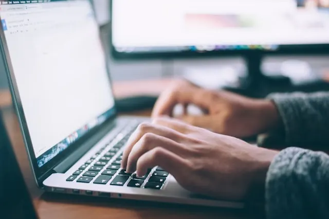 A person typing on their laptop