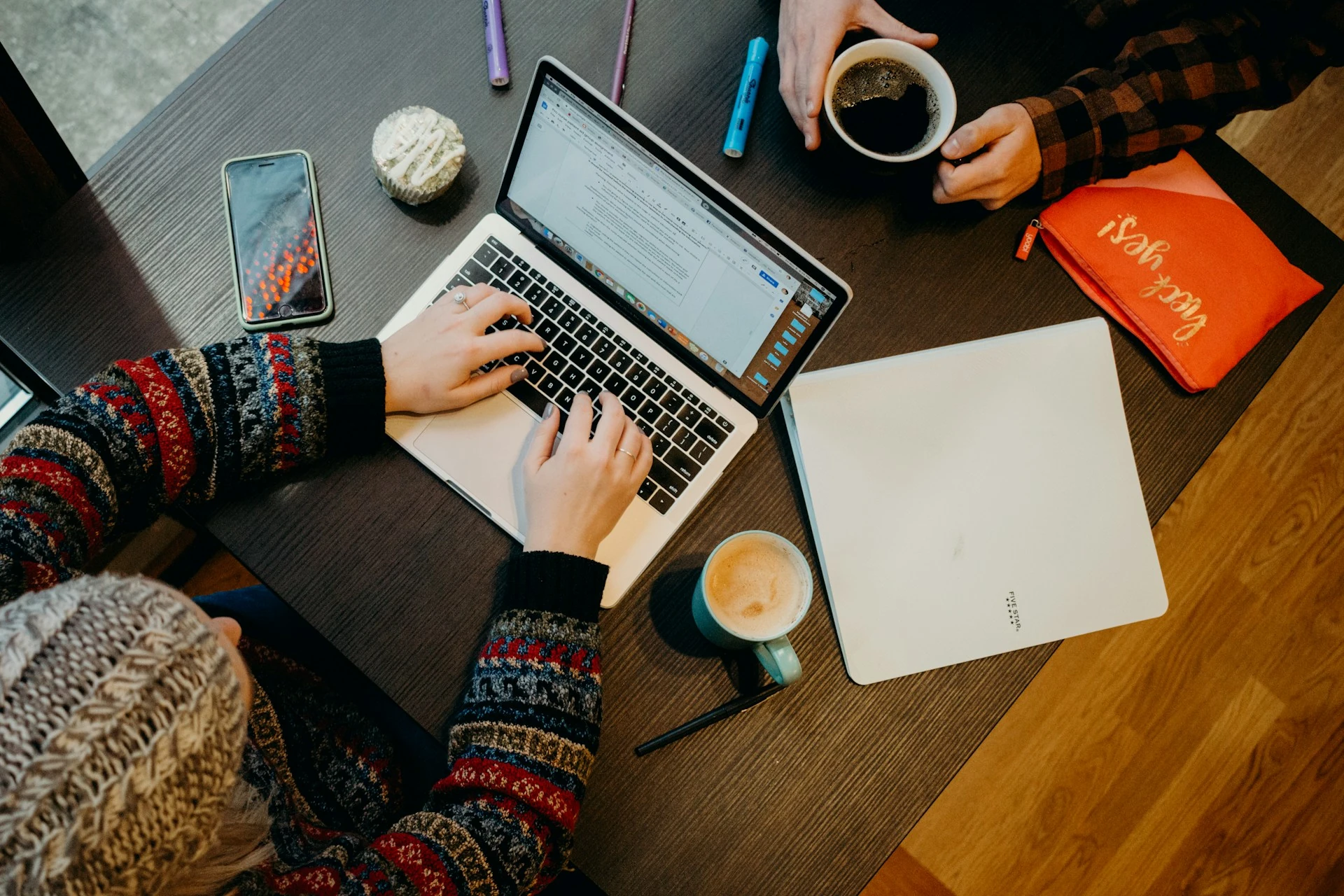 A person using a laptop with a cup of coffee on the table.